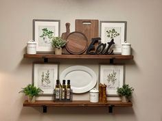 two wooden shelves holding plates, pictures and other kitchen utensils on top of each shelf