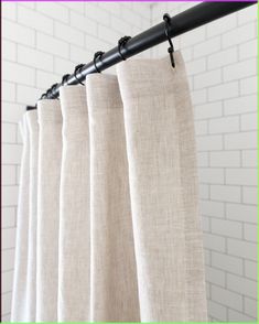 white curtains hanging on a black rod in front of a brick wall and tile floor