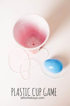 a plastic cup game with two blue and pink spoons next to it on a white surface