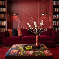 a living room filled with furniture and bookshelves next to a red couch in front of a book shelf