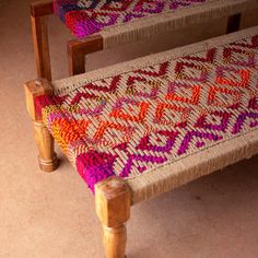 two wooden benches with colorful knitted seats on top of each other in a room