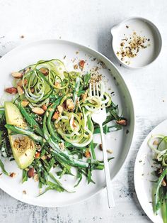 a white plate topped with green veggies and nuts