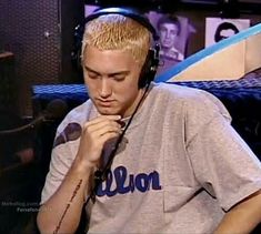 a man with headphones on sitting in front of a microphone and wearing a gray shirt