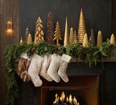 christmas stockings hanging from a mantel decorated with evergreen, pine cones and fir trees