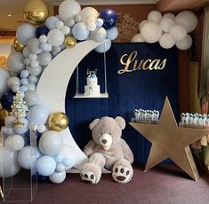 a teddy bear sitting in front of a backdrop with balloons