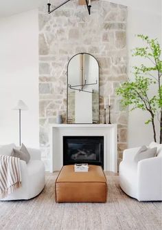 a living room with two white couches and a mirror on the wall above it