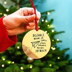 a hand holding a christmas ornament with writing on it