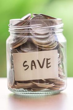 a jar filled with lots of coins sitting on top of a table next to a sign that says save