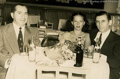 three people sitting at a table with drinks in front of them