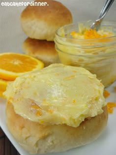 a plate topped with two rolls covered in cheese and orange zest next to a bowl of dip