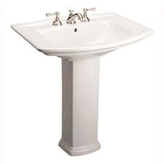 a white pedestal sink with two faucets