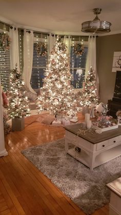 a living room decorated for christmas with white lights on the tree and presents under the window