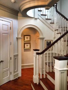 a white staircase with wood floors and wooden handrails in an elegant home setting