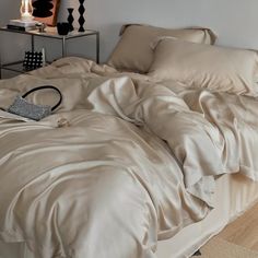 an unmade bed with beige sheets and pillows