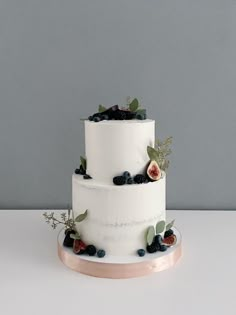 a three tiered cake with berries and leaves on it