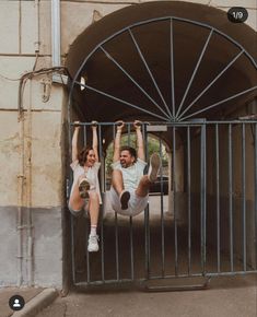 a man and woman hanging upside down in an iron gate