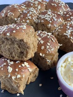 several rolls with sesame seeds and butter on a blue plate next to a container of mayonnaise