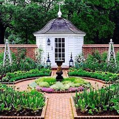 a garden with lots of different plants and flowers in the center, surrounded by brick walls