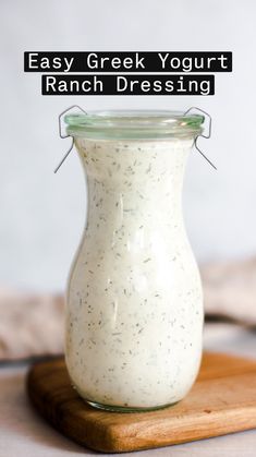 a jar filled with dressing sitting on top of a wooden cutting board