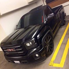 the black truck is parked in the parking space next to the yellow stripe on the floor