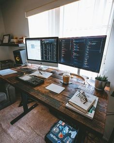 two computer monitors sitting on top of a wooden desk