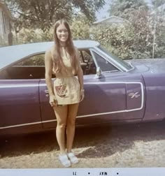 a woman standing in front of a purple car