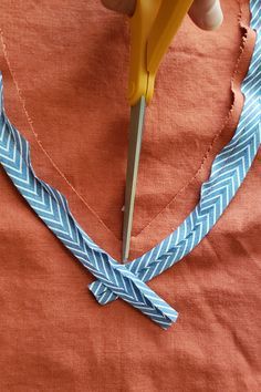 a person is cutting fabric with scissors on a piece of cloth that has been sewn together