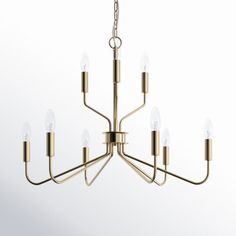 a brass chandelier with six lights hanging from the ceiling and four candles on each end