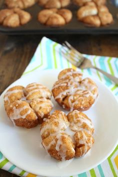 four cinnamon rolls on a white plate next to a muffin pan