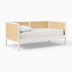 a white daybed with two pillows on top of it and an arm rest in front of the bed