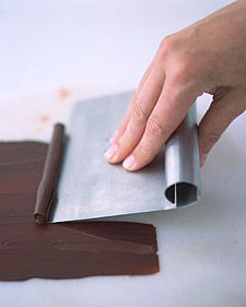 a person is using a piece of metal to make something brown and chocolate on the table