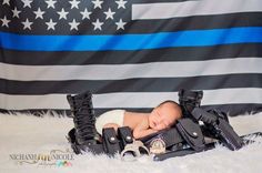 a newborn baby is posed in front of an american flag with police boots and handcuffs