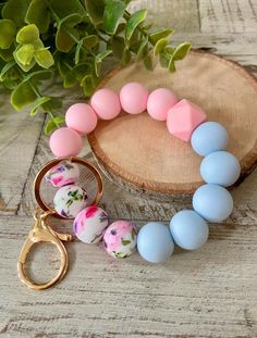 a pink, blue and white beaded bracelet next to a pair of gold scissors