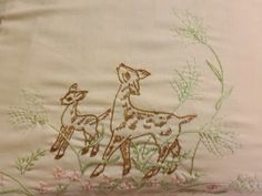 an embroidered pillow with two deers on it