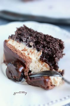 a piece of cake on a white plate with a spoon in it and chocolate frosting