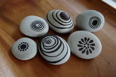 four rocks with designs on them sitting on a wooden table in front of a door