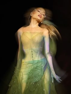 a woman in a green and yellow dress with her head tilted back to the side