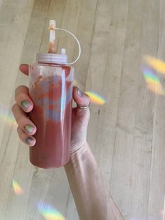 a person holding a pink and orange drink in their left hand with the lid up