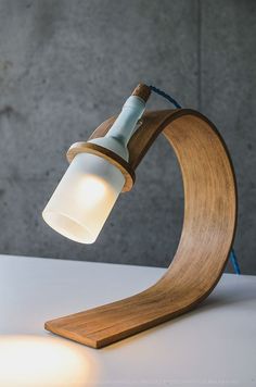 a wooden table lamp with a white light on it's base and a cord running through the bulb