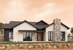 a white house with black shingles and stone walls in front of it on a cloudy day