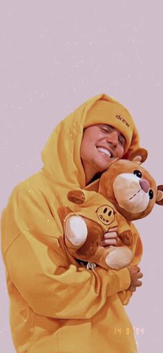 a person in a yellow bear costume holding a teddy bear and smiling at the camera