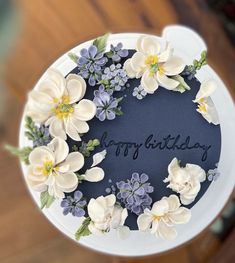 a birthday cake decorated with white and blue flowers