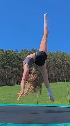 a woman doing a handstand on a trampoline