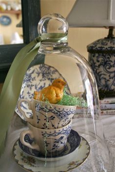 an image of a teacup with a bird in it under a glass dome on a table