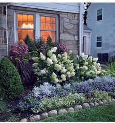 a house with flowers in front of it and a window on the side of the house