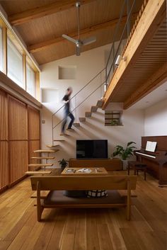 a man walking up the stairs in a living room next to a couch and piano