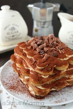 a stack of pancakes on a plate with powdered sugar and coffee in the background