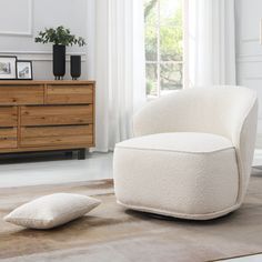 a white chair sitting on top of a wooden floor next to a dresser and window