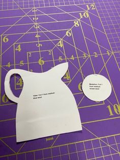 a cut out piece of paper sitting on top of a purple cutting mat with numbers