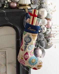 a christmas stocking hanging from a fireplace mantel with ornaments and decorations around it